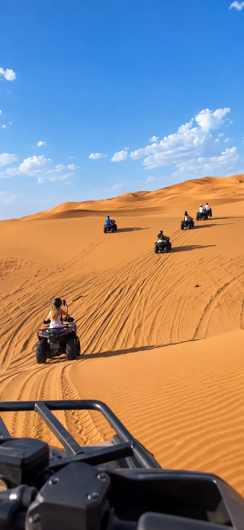 Quad riders crossing sandy dunes